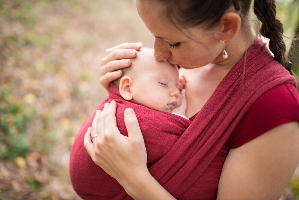 Babywearing mom and baby outside, kiss on forehead