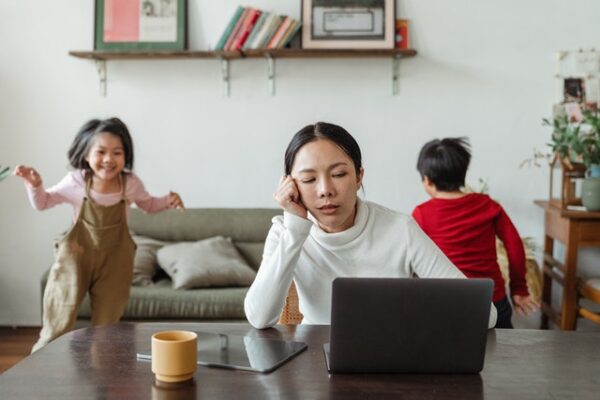 burned out mom working from home with children playing in the background