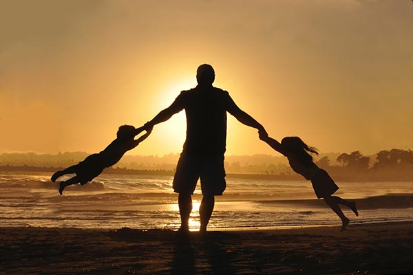 father playing with kids in sunset