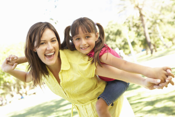 mother giving daughter ride on back in the park - finding joy in motherhood