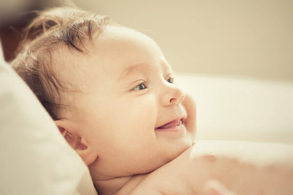 smiling baby relaxing on couch for article how to deal with sleep regression