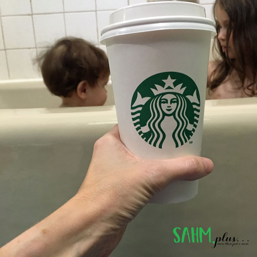Kids in the bathtub in the background, hand holding cup of starbucks coffee