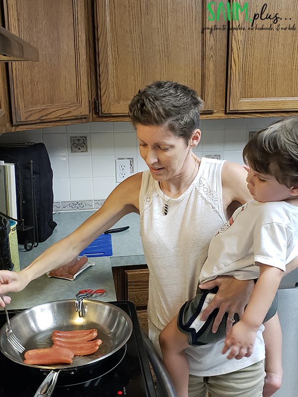 toddler on hip of stay at home mom cooking at the stove | sahmplus.com