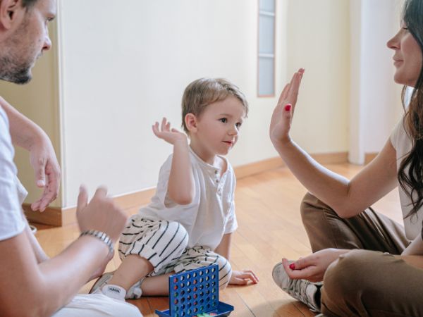 parents praising child after game of connect four - understanding parenting styles