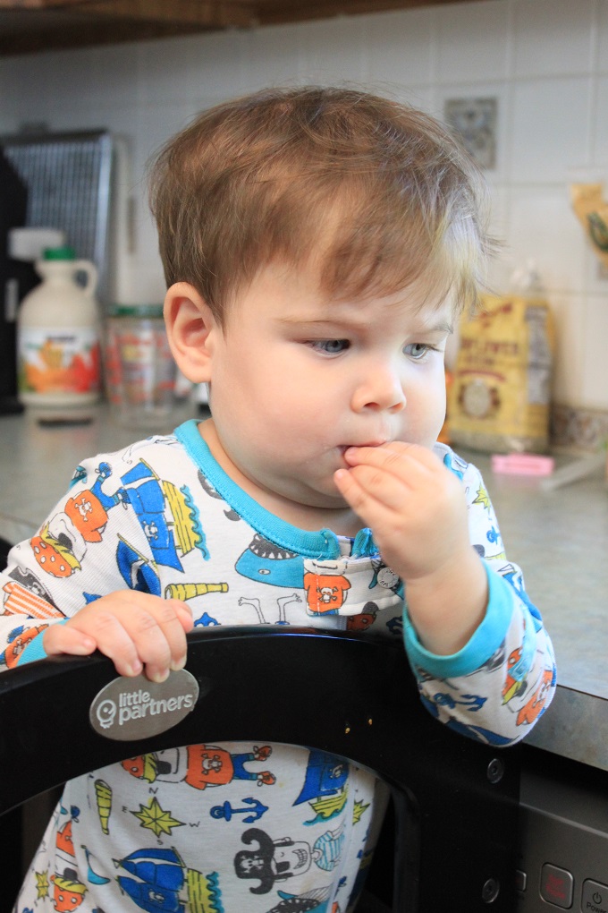 Toddler using The Original Learning Tower from Little Partners. Snacking on ingredients for trail mix cereal bars. via www.sahmplus.com