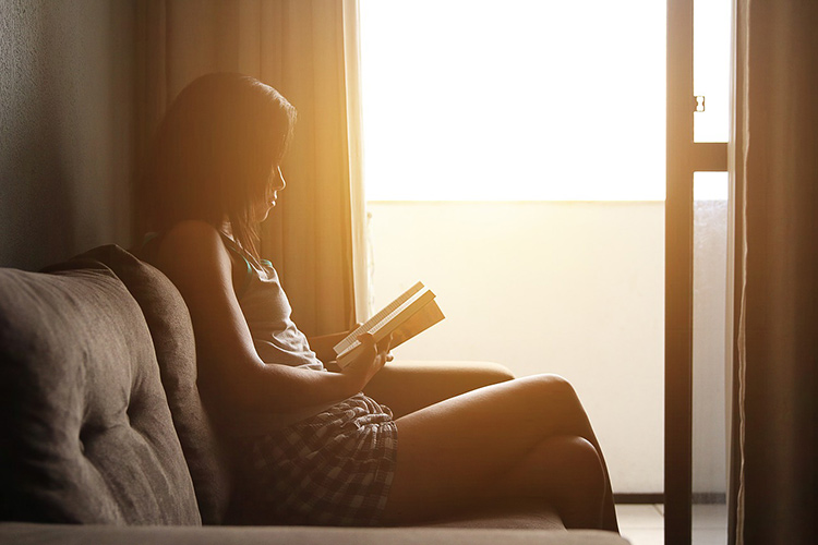 woman practicing self-care reading a book