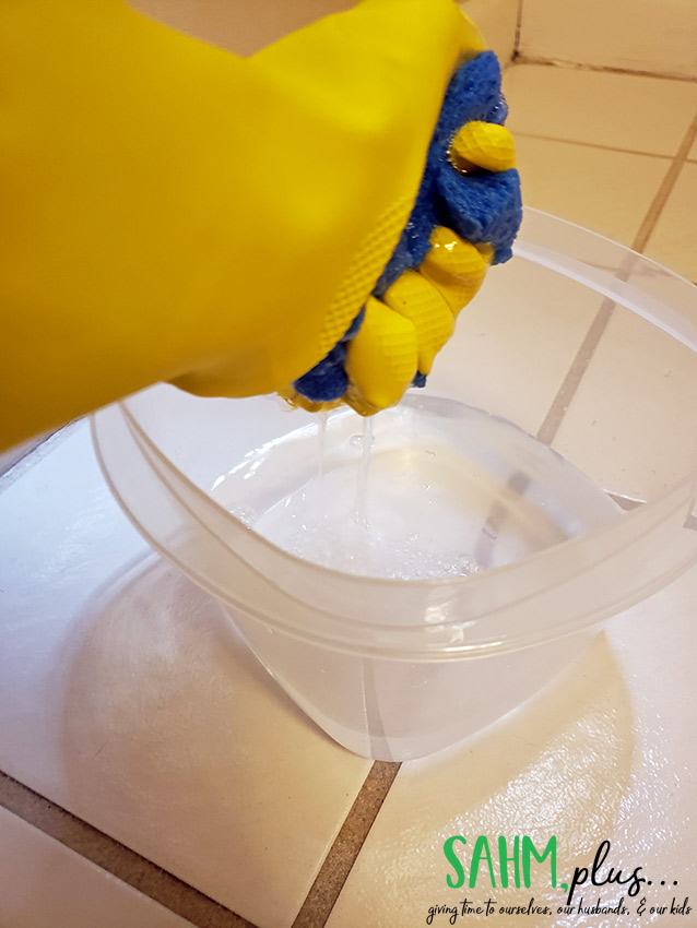 wringing out sponge to clean tile floors with vinegar and water | sahmplus.com